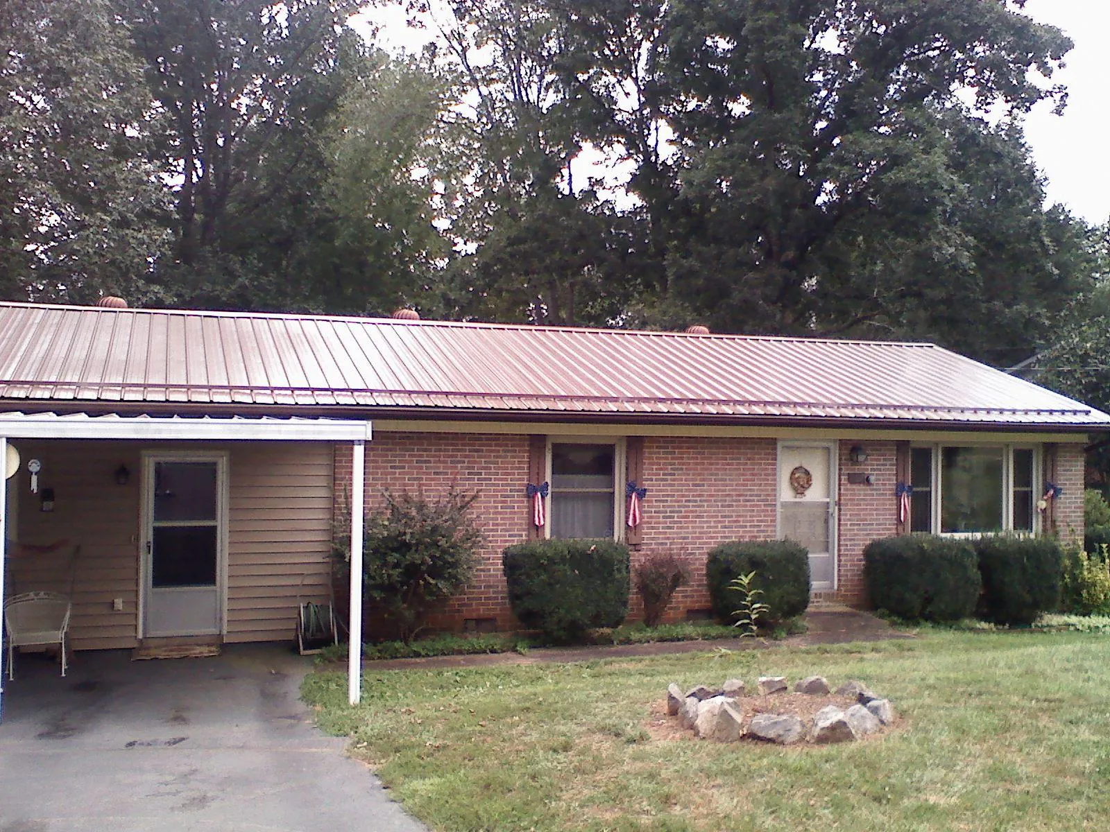 Bronze metal roof and carport on a brick ranch home — Roof Repair work by our crew in Hutchinson
